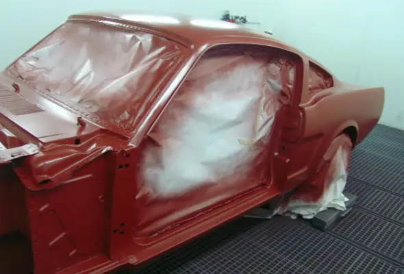 Karosserie eines Ford Mustang mit frischem rotem Basislack in der Lackierkabine