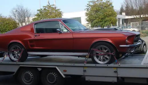 Frisch lackierter Ford Mustang Fastback in kupferrotem Metallic auf dem Fahrzeugtransporter