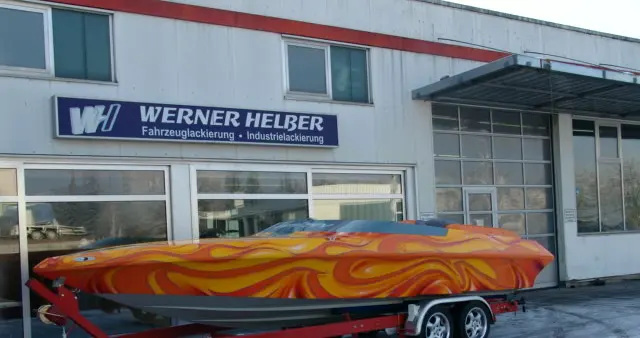 Rennboot mit mehrfarbiger Flammen-Airbrushlackierung auf dem Trailer vor dem Betriebsgebäude